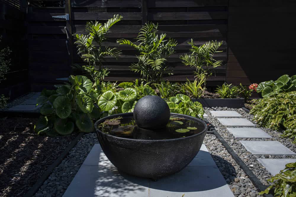Black water feature with pavers and garden plants